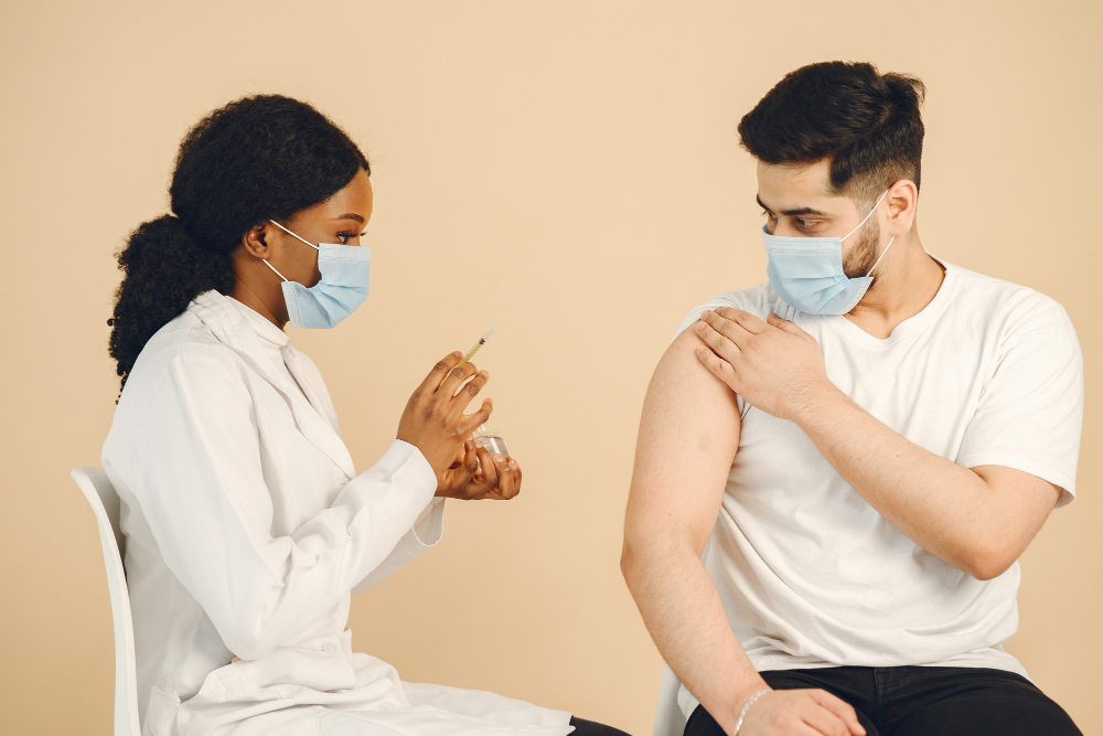 African american doctor giving vaccine shot to a man. both wearing masks, isolated. vaccination.
